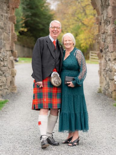 Customer wearing his kilt after a waist extension and apron adjustment, standing with his wife