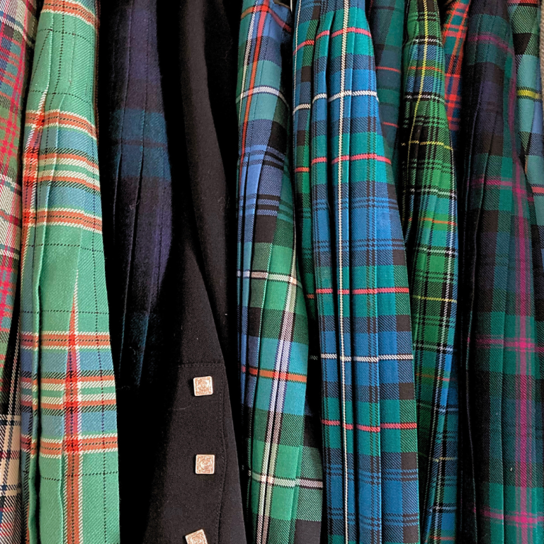 Kilt alteration service Glasgow A collection of kilts in various colours and patterns hanging together.