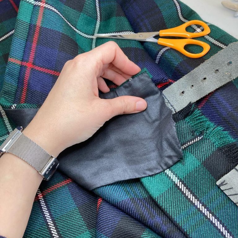 Kilt repair service Glasgow. Kilt Expert Alteration A hand sewn kilt with scissors nearby.